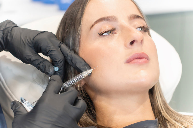 Person receiving a facial injection with medical gloves on hands