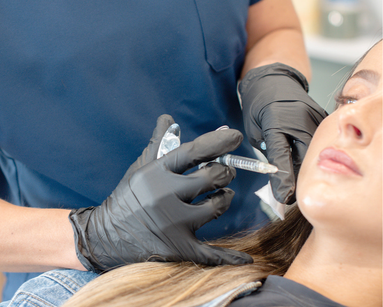 Person receiving a facial injection from a professional in a clinical setting.