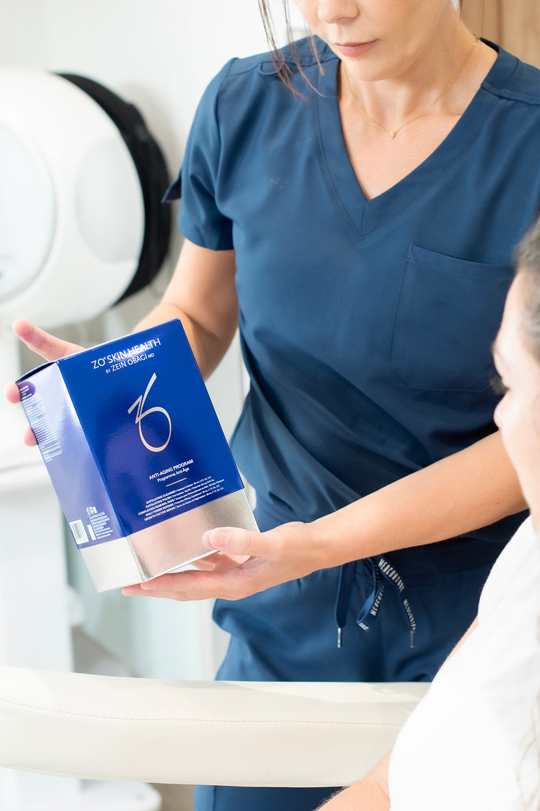 Person in blue scrubs holding a box of treatment in a clinical setting