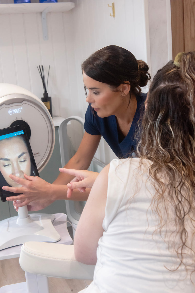 Woman using a device on another woman's face in a clinical setting