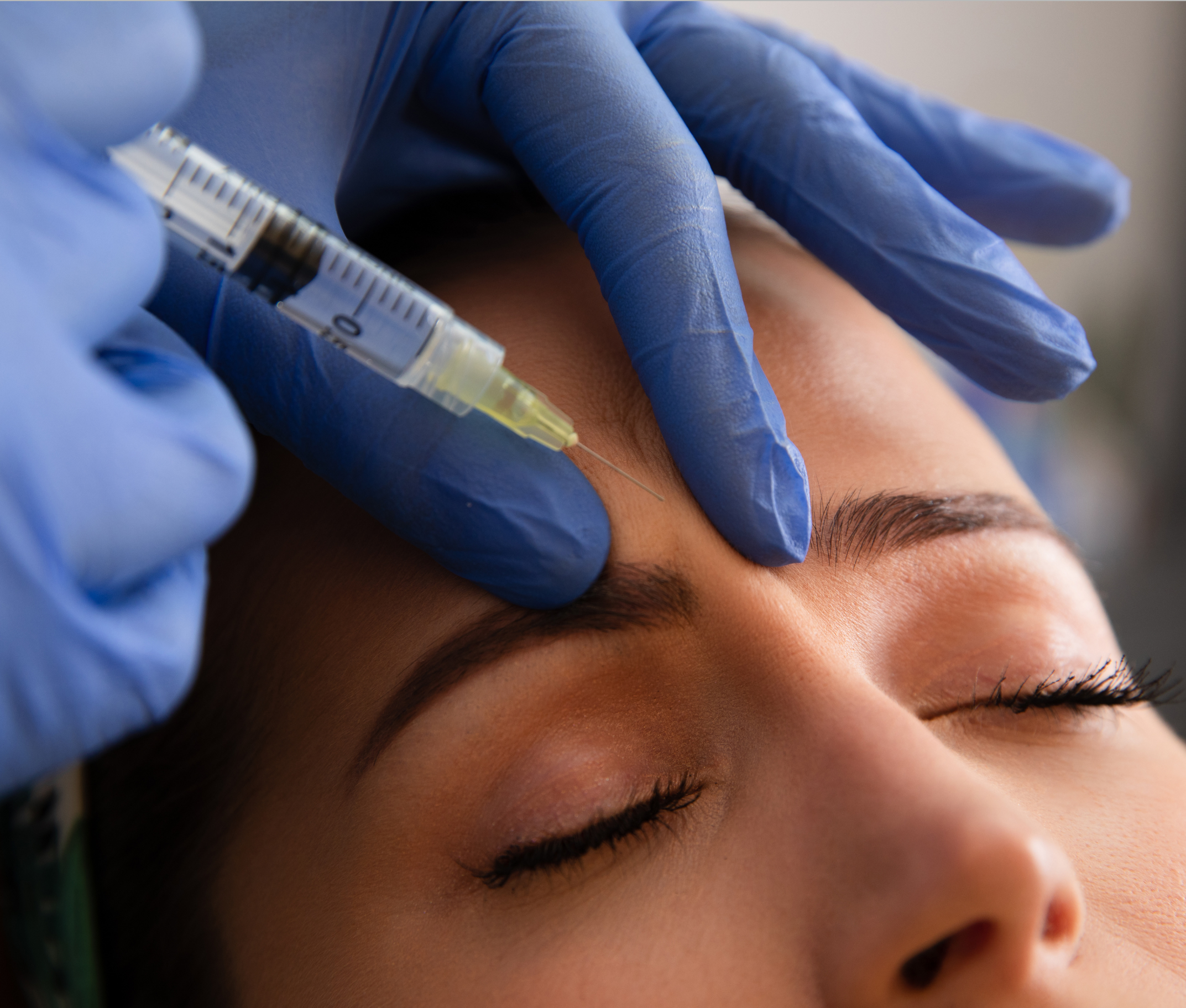 Person receiving a facial injection with blue gloves and a syringe.
